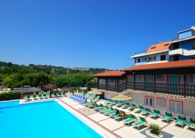 Piscina affiancata da edificio con tetti rossi.