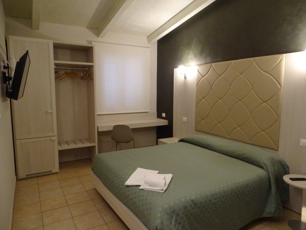 Camera con letto verde e parete nera. Guarda robe aperto e finestra con tendina chiusa.