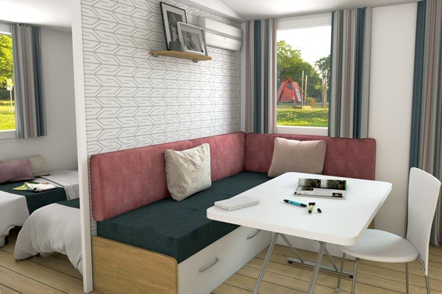 Salotto accogliente con divano ad angolo, tavolo bianco e finestre con tende a strisce colorate.