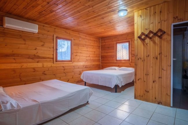 Interno di una stanza rivestita in legno, con due letti e un condizionatore.