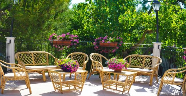 Terrazza con mobili in rattan e piante fiorite.