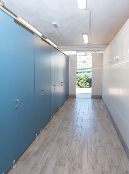 Corridoio con cabina blu e porta aperta sullo sfondo.