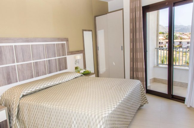 Una camera con letto matrimoniale, armadio, balcone e vista esterna.