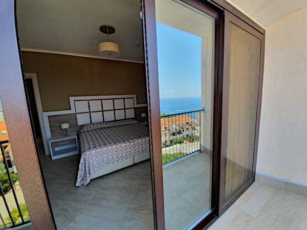 Camera d'albergo vista dal balcone, con letto matrimoniale e panorama marino.