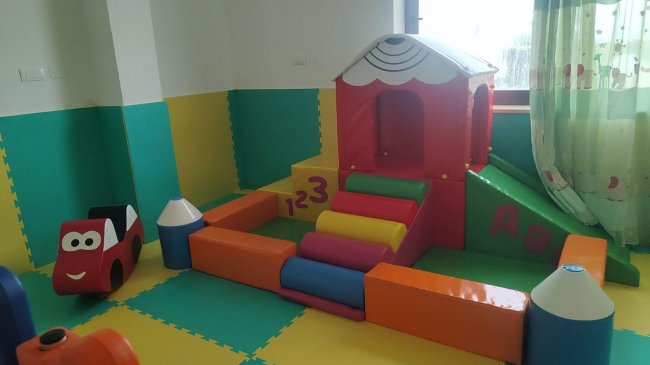 Un'area giochi per bambini con blocchi colorati e una piccola casetta.
