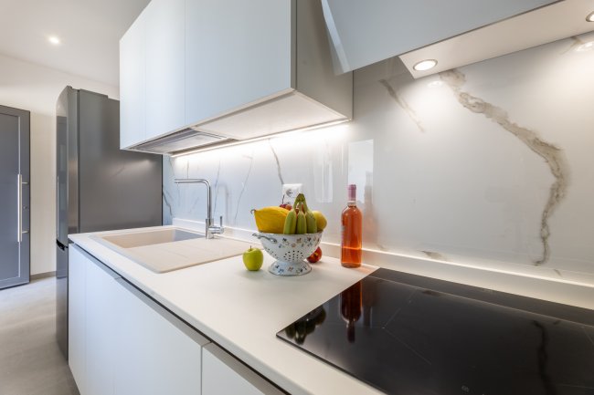 Cucina bianca elegante con frutta sul piano di lavoro.