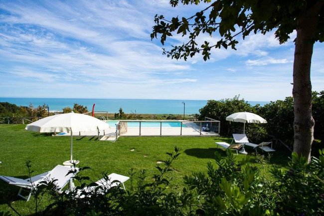Piscina con lettini e ombrelloni, vista sull'oceano.