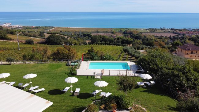 Panoramica di piscina, prato e mare sullo sfondo.