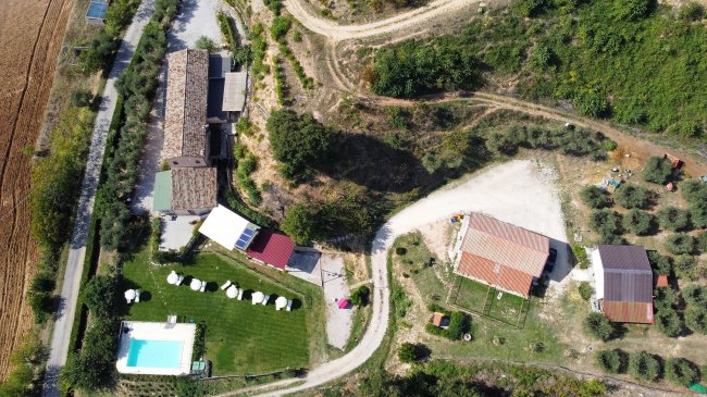Vista aerea di un complesso con piscina, edifici e strade sterrate.