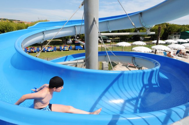 Persona su uno scivolo acquatico blu a spirale in un parco.