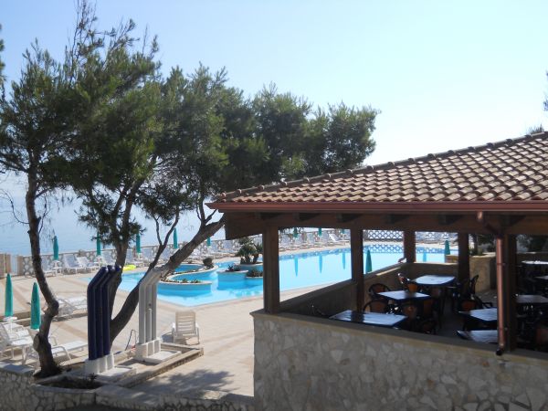 Piscina con lettini e ombrelloni vicino a un ristorante.