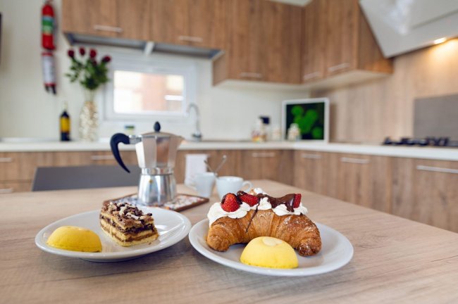 Tavolo con croissant, dolci e moka in cucina moderna.