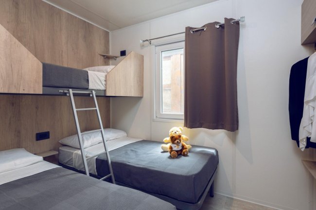 Camera con letto a castello e singolo, orsetto di peluche sulla coperta.