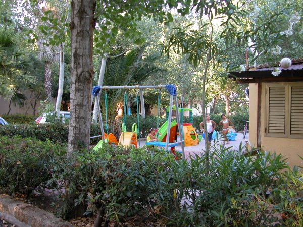Un parco giochi con altalene colorate e piante tutt'intorno.