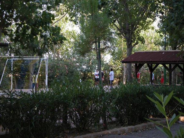 Campo da gioco all'aperto con rete da calcio e persone.