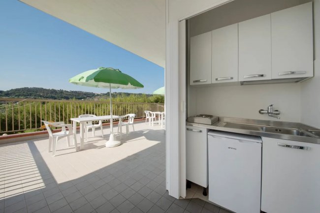 Terrazza con ombrelloni verdi e vista collinare.