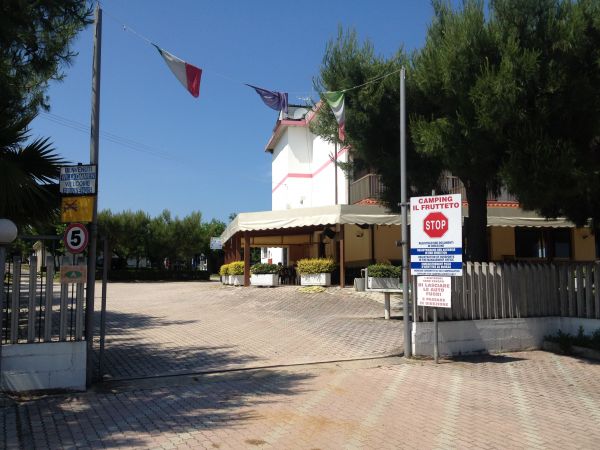 Ingresso di un campeggio con bandiere e cartelli.