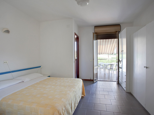 Camera da letto con letto matrimoniale, armadio e accesso alla terrazza.