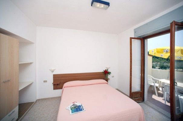 Camera da letto semplice con letto matrimoniale e porta che dà su un balcone.