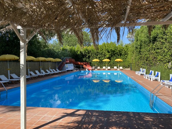 Piscina con lettini e ombrelloni gialli.