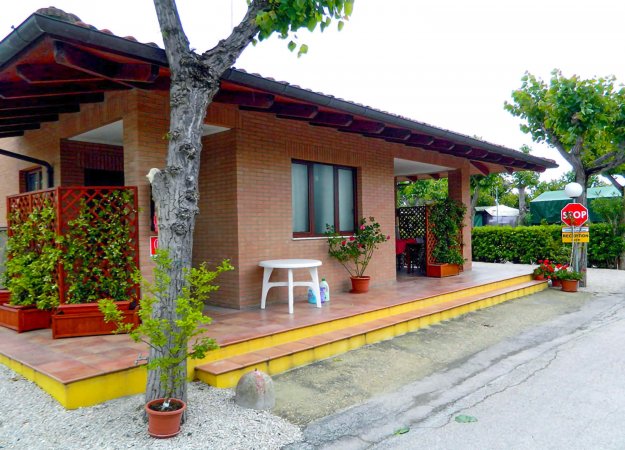Una casa in mattoni con veranda, tavolo bianco e piante in vaso.