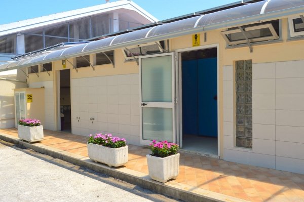 Edificio con ingressi aperti e fioriere sul marciapiede.