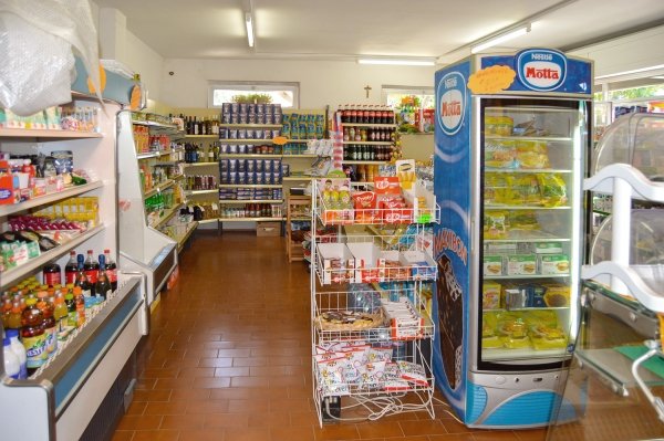 Negozio di alimentari con scaffali pieni e frigorifero.
