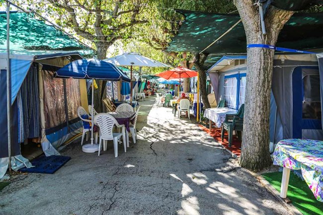 Un'area campeggio con tende, sedie e ombrelloni colorati.