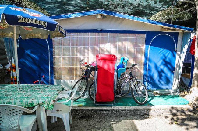 Tenda da campeggio con tavolo, sedie e biciclette davanti.