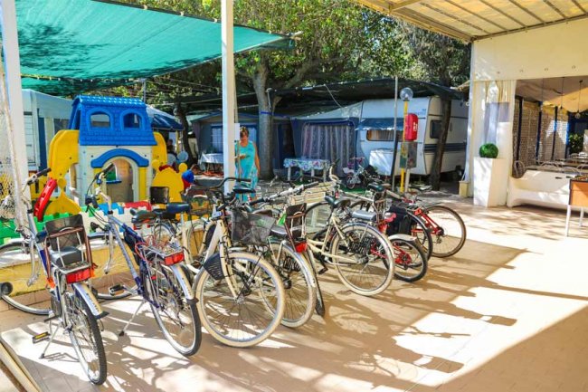 Biciclette parcheggiate vicino a roulotte e area giochi all'aperto.