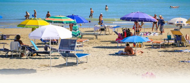 Spiaggia affollata con ombrelloni colorati e bagnanti in riva al mare.