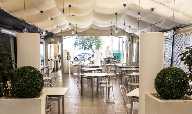 Ristorante con tettoia bianca, tavoli e sedie.