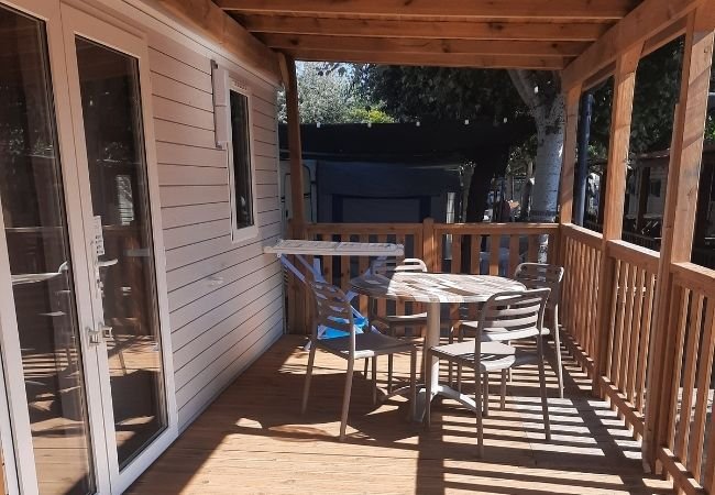 Tavolo rotondo con sedie su una veranda di legno sotto un tetto.