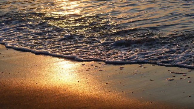 Onde che si infrangono su una spiaggia al tramonto.