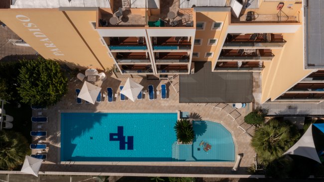 Veduta aerea di una piscina rettangolare con lettini e ombrelloni attorno.