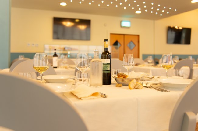 Tavola apparecchiata con bicchieri di vino, pane e bottiglie in un ristorante elegante.