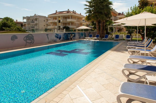 Una piscina all'aperto con lettini e ombrelloni.