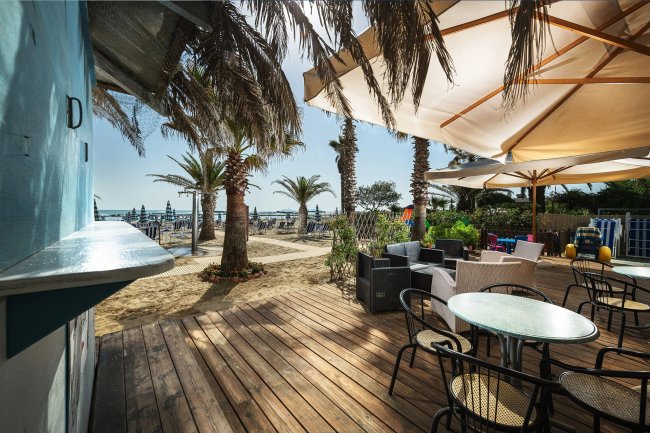 Terrazza con tavoli e ombrelloni vicino alla spiaggia.