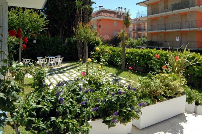 Un giardino con fiori colorati e tavoli in plastica.