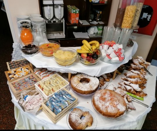 Buffet con dolci, frutta, succhi, e cereali. Tavolo ben imbandito.