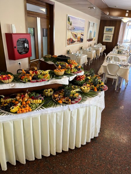 Buffet di frutta decorata con vista su una sala da pranzo apparecchiata.