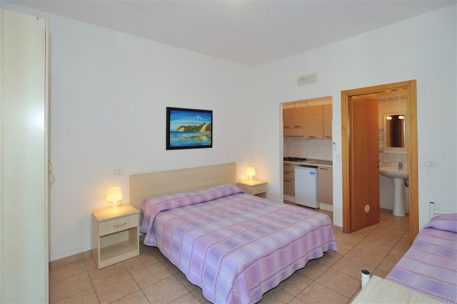 Camera da letto con letto matrimoniale e copriletto a righe.