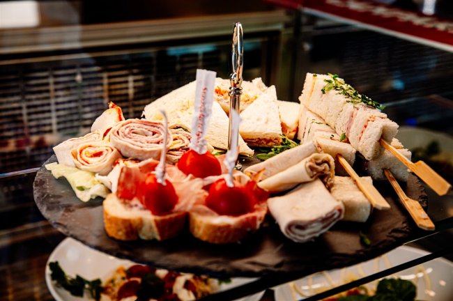 Vassoio di sandwich assortiti e stuzzichini su un piatto elegante.