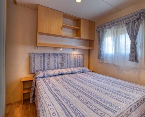 Camera con letto matrimoniale, testiera imbottita e tende abbinate.