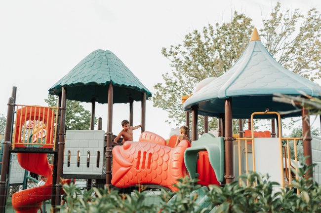 Bambini che giocano su una colorata struttura di un parco giochi all'aperto.