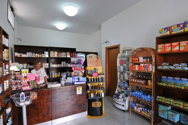 Interno di un negozio con scaffali di prodotti e una persona al bancone.