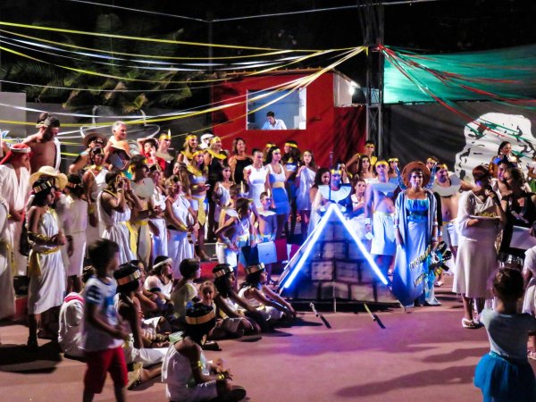 Un gruppo di persone in scena con abiti colorati e decorazioni luminose.
