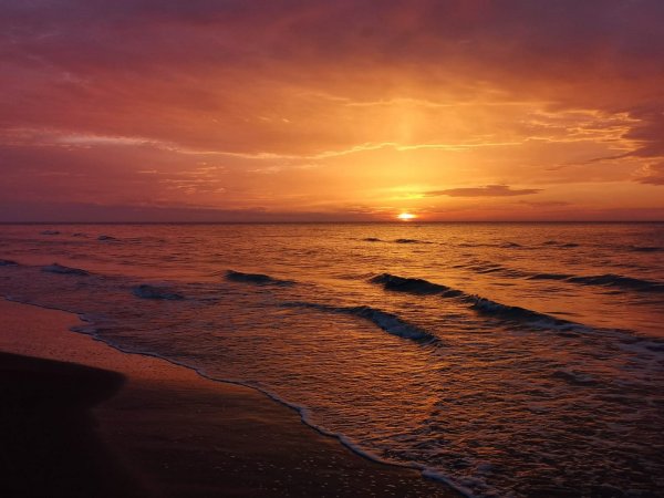 Tramonto sul mare con cielo arancione e onde leggere.