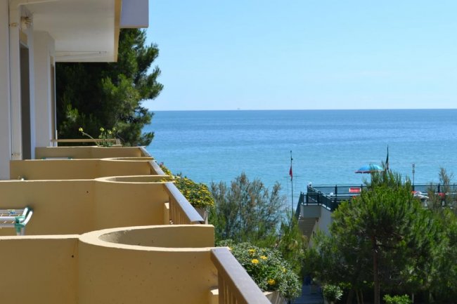 Balconi con vista sul mare e vegetazione.
