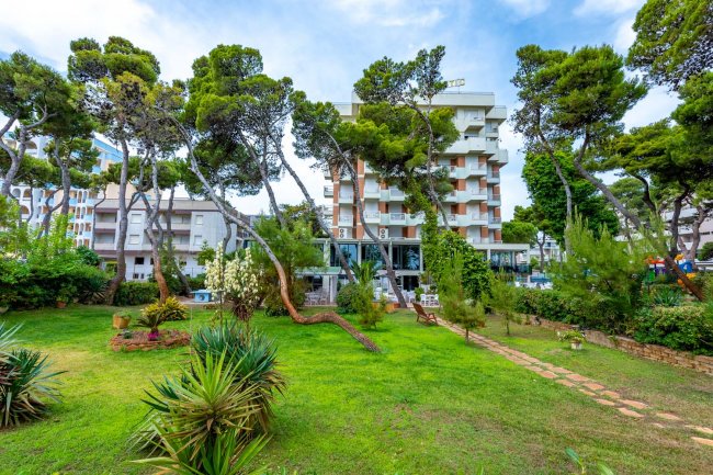 Un hotel circondato da un giardino verde e alberi.